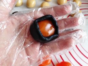 7.	取一个黑芝麻团，用手按扁，中间放一个蛋黄，再将蛋黄包住，