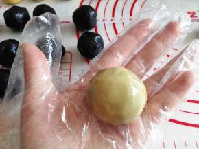 8.	取一个面团，用手按扁，中间放包了蛋黄的黑芝麻团，用虎口一点一点向上推着包，把其包好