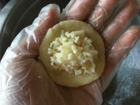 取一个土豆球，压扁，包入马苏里拉芝士，然后收口收紧