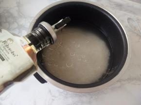 按比例加入水，我一般按经验用手试，手掌平放在米上，水没过手背即可。一般可按1：1或1：1.2来，这个请根据自已的喜好。我还喜欢在米中加入几滴食用油。