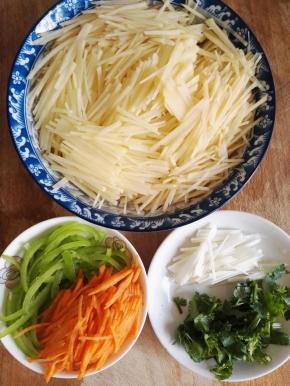 2、土豆去皮切丝，青椒和胡萝卜切丝，葱白切丝，香菜切碎。