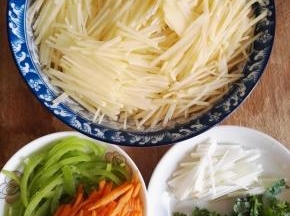 2、土豆去皮切丝，青椒和胡萝卜切丝，葱白切丝，香菜切碎。