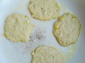 7、锅烧热后，倒入食用油，将红薯面糊用手团成圆形，放入锅中，再用手压成薄饼进行烙制。