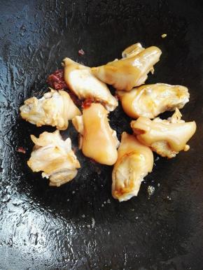5、待颜色变成棕色有大泡沫时倒入猪蹄，翻炒猪蹄，加入郫县豆瓣酱翻炒，待猪蹄均匀上色。