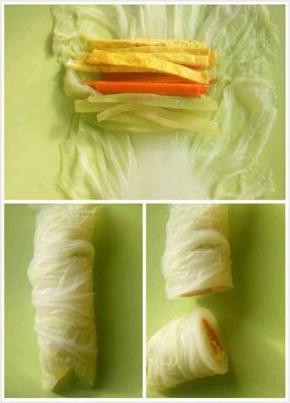 然后白菜叶平放在菜板上，把莴笋丝，胡萝卜丝，鸡蛋丝放在白菜叶里面卷起来，然后对半切开