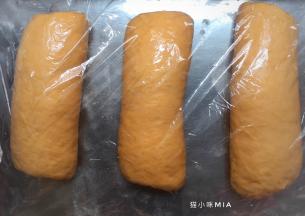 将一次松弛好的面团擀成长舌状，从上往下卷起，用保鲜膜盖好，再次松弛10分钟