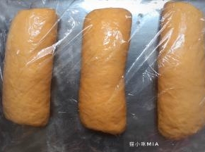 将一次松弛好的面团擀成长舌状，从上往下卷起，用保鲜膜盖好，再次松弛10分钟