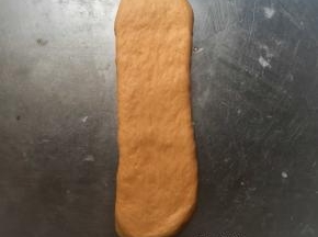 将二次松弛好的面团再擀开，从上往下卷起，放入吐司盒中