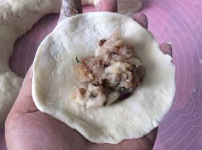 搓圆压扁擀成中间厚两边薄的面皮，加入肉馅
