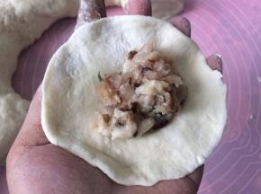 搓圆压扁擀成中间厚两边薄的面皮，加入肉馅