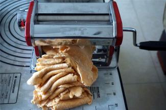 开始用最厚的7档压面，初次压面2次，将盆里的干粉里包到面块中，然后放入压面机压面，压两次后就没有干粉了。