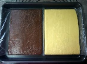 隔着保鲜袋擀成1厘米厚的香草味面片。同样的方式，制作出巧克力味面片。做好后，将面片放入冰箱冷冻层冷冻30分钟左右。