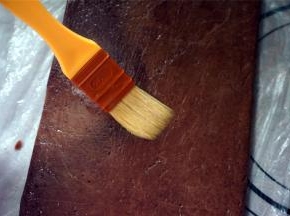 将冻硬了的面片取出，撕开保鲜袋，在其中一片面片上刷上一层全蛋液。