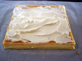 待蛋糕体冷却至温温的状态时，倾斜切去收尾，抹上打发好的淡奶油。