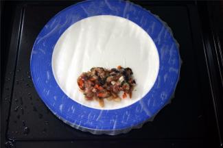 将圆形的春卷皮摊到碟子上，然后放上肉馅，像包班戟一样包起来
