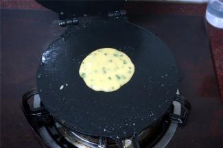 蛋卷磨具在燃气炉上烧热后勺入一勺面糊，合上蛋卷机。