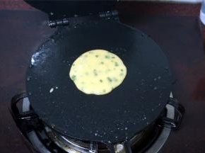 蛋卷磨具在燃气炉上烧热后勺入一勺面糊，合上蛋卷机。