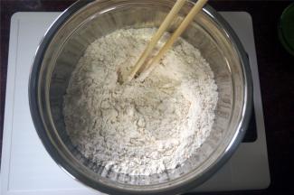 将325克高筋粉倒进深碗里，加入一个全蛋，2克食盐，用筷子搅拌一下。