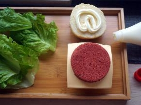 然后从底部往上组装汉堡，顺序是面包底，红丝绒蛋糕片，芝士片，红丝绒蛋糕片，生菜，面包面。