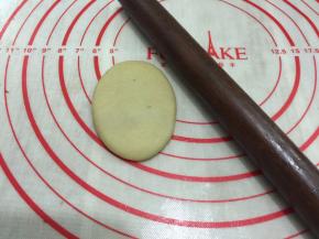 将包好的油酥皮收口朝上，用擀面杖将它擀成长条