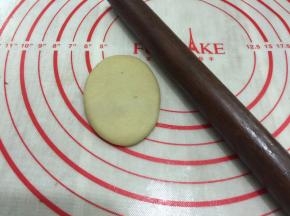 将包好的油酥皮收口朝上，用擀面杖将它擀成长条