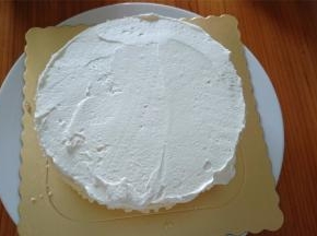 由于是大热天，除了开启冷气来做蛋糕外，淡奶油打发后也需要先冷藏半小时再用来装裱蛋糕。首先抹一层奶油。