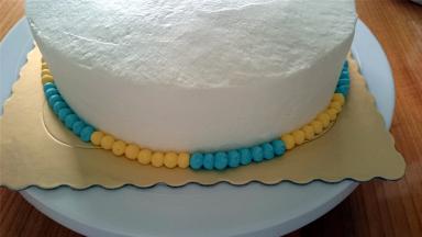 取出蛋糕，用黄色，蓝色的奶油分别挤出小圆点装饰蛋糕脚。