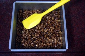 趁热将核桃仁倒入到饼干底上，并推压平整，然后，将模具重新放入烤箱，用原来的温度继续烤8~10分钟后取出，冷却后切块，密封保存。