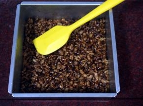 趁热将核桃仁倒入到饼干底上，并推压平整，然后，将模具重新放入烤箱，用原来的温度继续烤8~10分钟后取出，冷却后切块，密封保存。