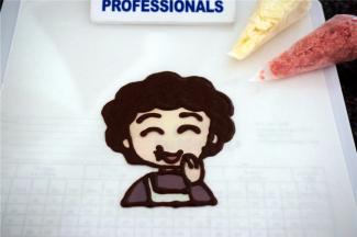 准备白色，黑色，红色，水蜜桃颜色的巧克力，准备转印丸子妈妈。先用黑色巧克力描边并填充头发，画出五官。