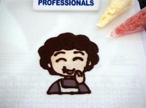 准备白色，黑色，红色，水蜜桃颜色的巧克力，准备转印丸子妈妈。先用黑色巧克力描边并填充头发，画出五官。