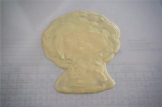 然后脸部填上水蜜桃颜色巧克力，嘴巴和衣服用红色巧克力填上，其余用白色巧克力填上，最后白色巧克力覆盖转印整体，放入冰箱冷冻至硬。