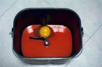 将胡萝卜汁，鸡蛋放入面包桶里。对角分别放入盐和糖。