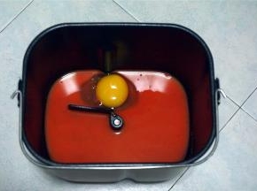 将胡萝卜汁，鸡蛋放入面包桶里。对角分别放入盐和糖。