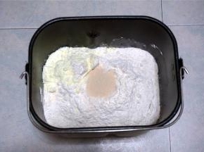 然后加入高筋粉，在其中一个角放入奶粉。中间挖空放入酵母。