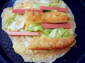 关火。洒少许葱花儿，将西生菜、香肠和油条摆在上面