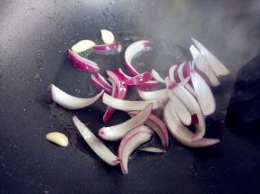 热锅热油，爆香蒜瓣后，下洋葱炒至断生。