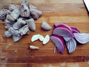 将鸡心在80度左右的热水中焯一下，大约五六分熟，捞出沥净水分。切蒜苔，洋葱和蒜瓣。