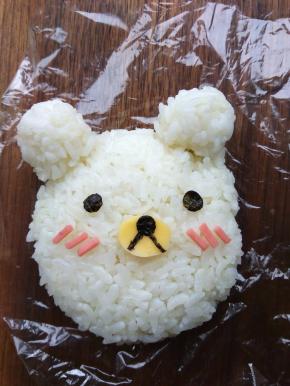 将少许米饭放在保鲜膜中，团出两只耳朵。并用奶酪片和寿司紫菜，刻出五官。放在一边备用。