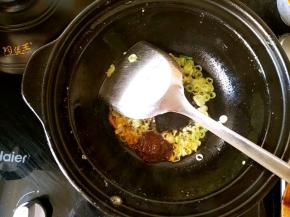 利用锅中的余油爆香葱花，再放一勺香辣酱翻炒。