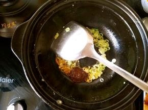 利用锅中的余油爆香葱花，再放一勺香辣酱翻炒。