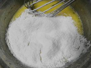 撒入过筛低粉，用蛋抽画1字，挑起蛋黄糊，让她自由的滴落，混合的更均匀 最后取抹刀，把蛋盆边缘部分刮进去，拌匀