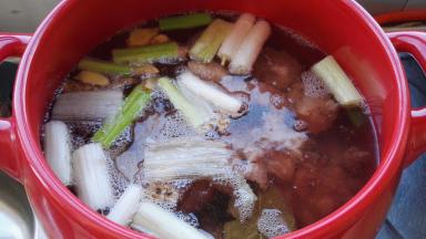 同时砂锅添水，放入葱及调料盒，大火烧开，把焯水的排骨取出放砂锅内。