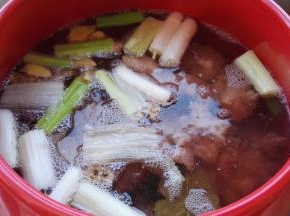 同时砂锅添水，放入葱及调料盒，大火烧开，把焯水的排骨取出放砂锅内。