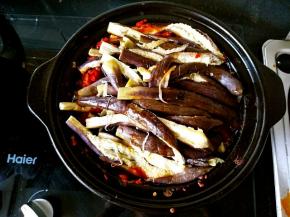 把准备好的茄子条放进锅中，用筷子翻拌均匀。加入少许盐。