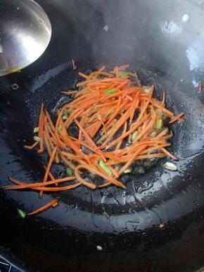 再把胡萝卜丝下入锅中翻炒，此时如果有洋葱可以随胡萝卜一起入锅。
