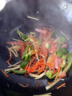 待胡萝卜炒一会8.9份熟之后把青椒和香肠土豆丝一起下锅翻炒。