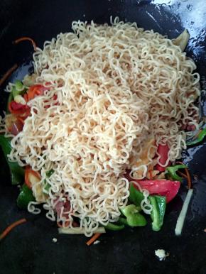 鸡蛋翻炒几下后，这时候我们就要把主材料机也就是方便面加入锅中了。