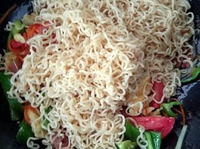 鸡蛋翻炒几下后，这时候我们就要把主材料机也就是方便面加入锅中了。