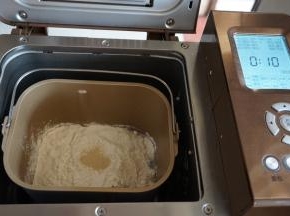 在面粉顶端加上酵母，面包桶放入东菱1352AE-3C面包机内，选择和面程序，默认10分钟